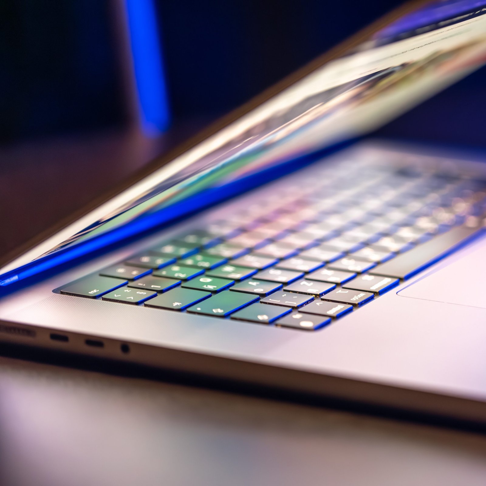 a laptop computer with a half open screen on a dark background.